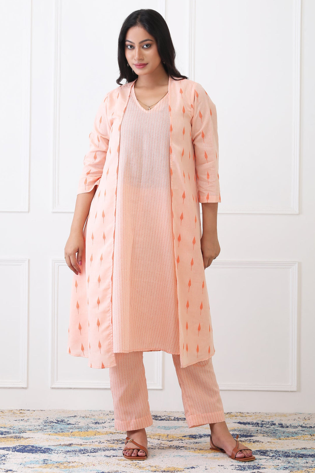 Woman wearing a peach kurta with a matching long jacket on a white background