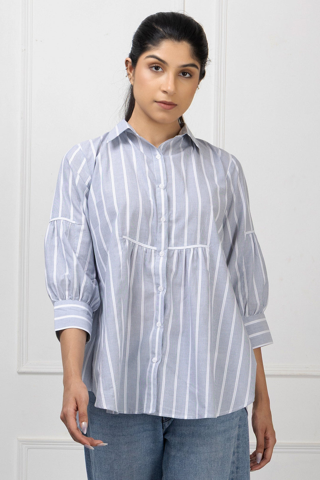Woman wearing a white and blue striped shirt against a white background