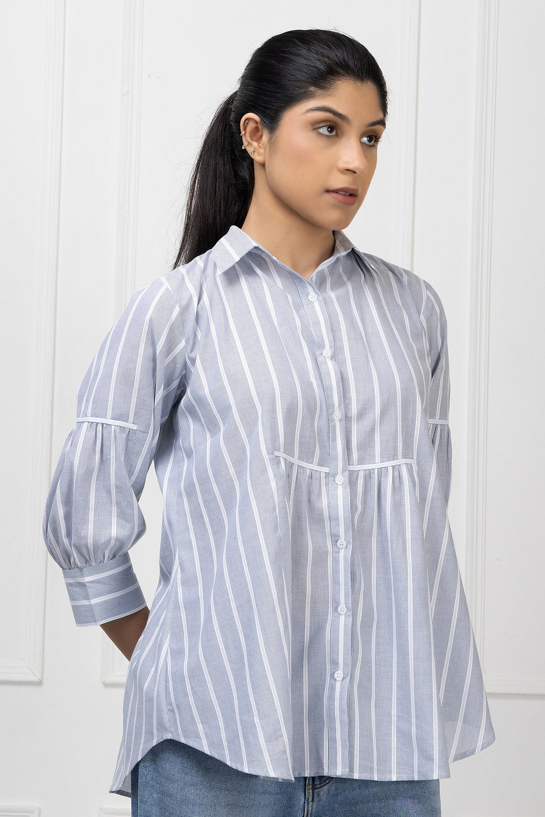 Woman wearing a light blue and white striped shirt against a white background