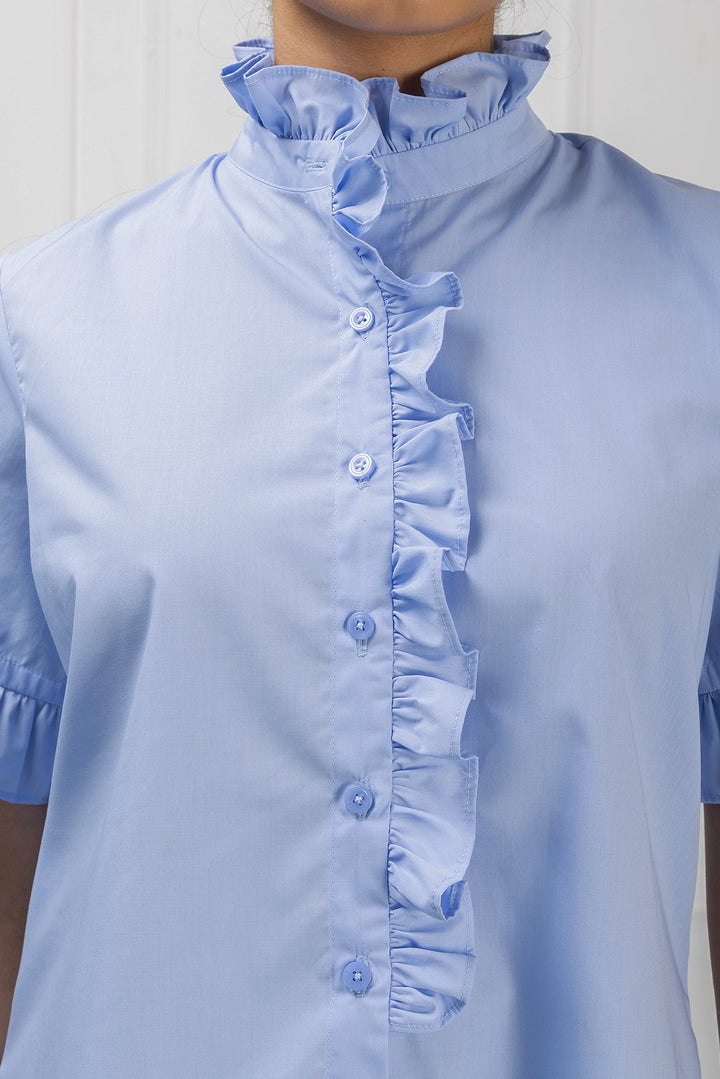 Light blue blouse with ruffled collar and cuffs on a plain background