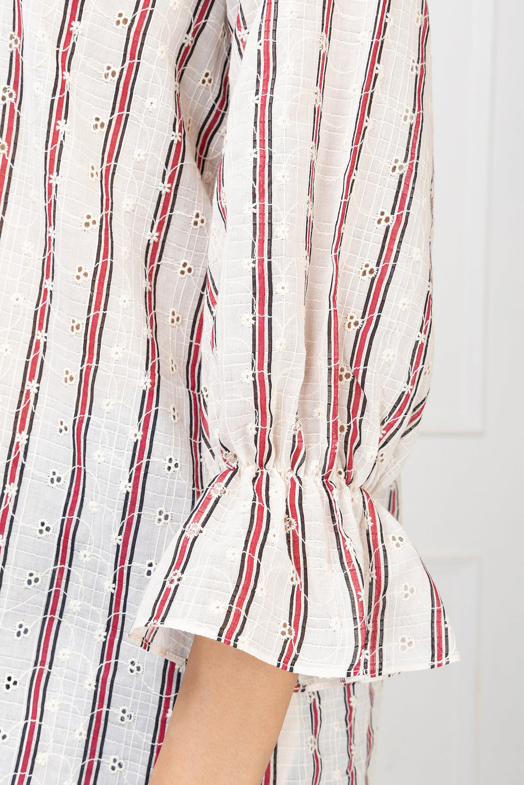 Close-up of a white dress with red and black stripes on a white background
