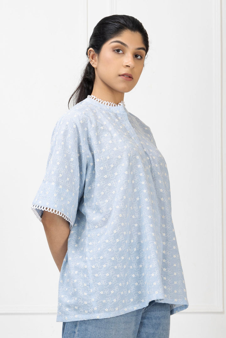 Woman wearing a light blue polka dot shirt with lace trim on a white background