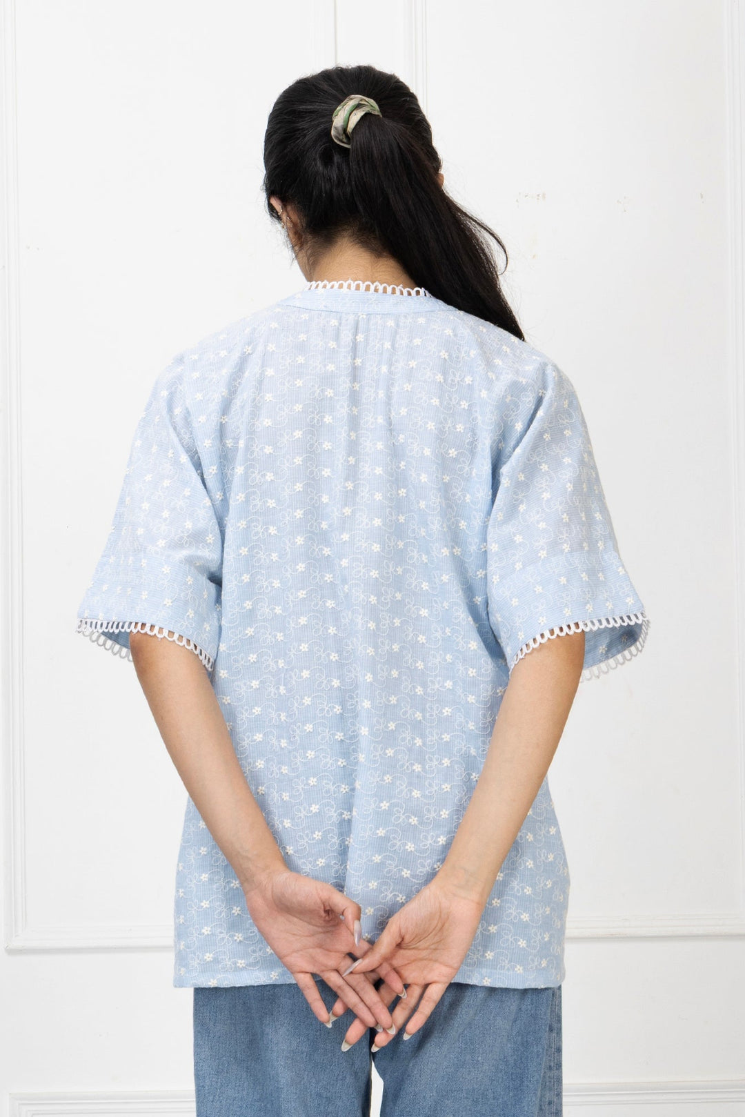 Person wearing a light blue polka dot shirt with white trim against a white background