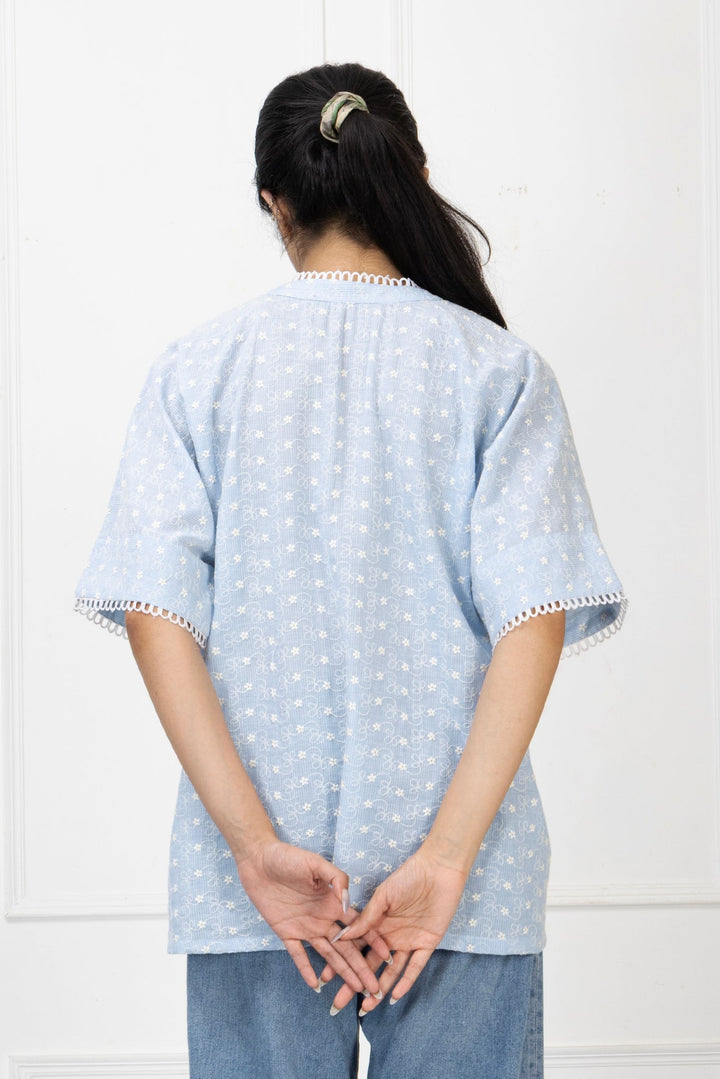 Person wearing a light blue polka dot shirt with white trim against a white background