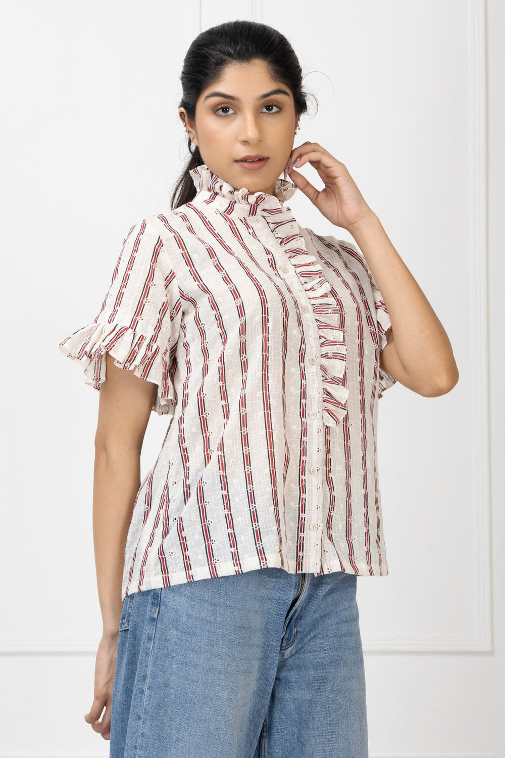 Woman wearing a striped shirt with ruffled sleeves against a white background