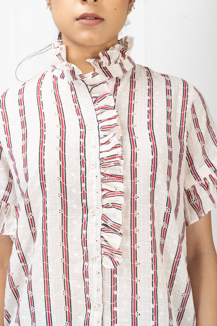 Person wearing a white shirt with red and black striped patterns on a plain background