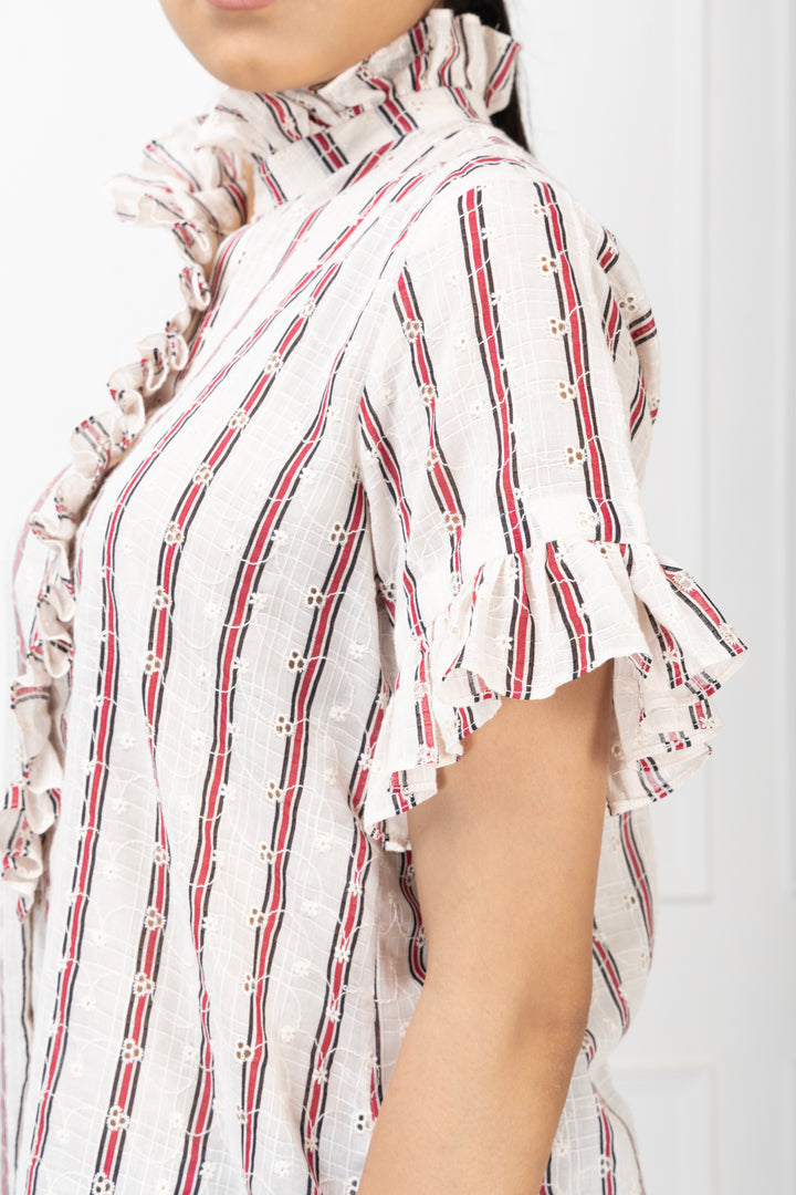 Close-up of a person wearing a white blouse with red and black striped patterns on a white background