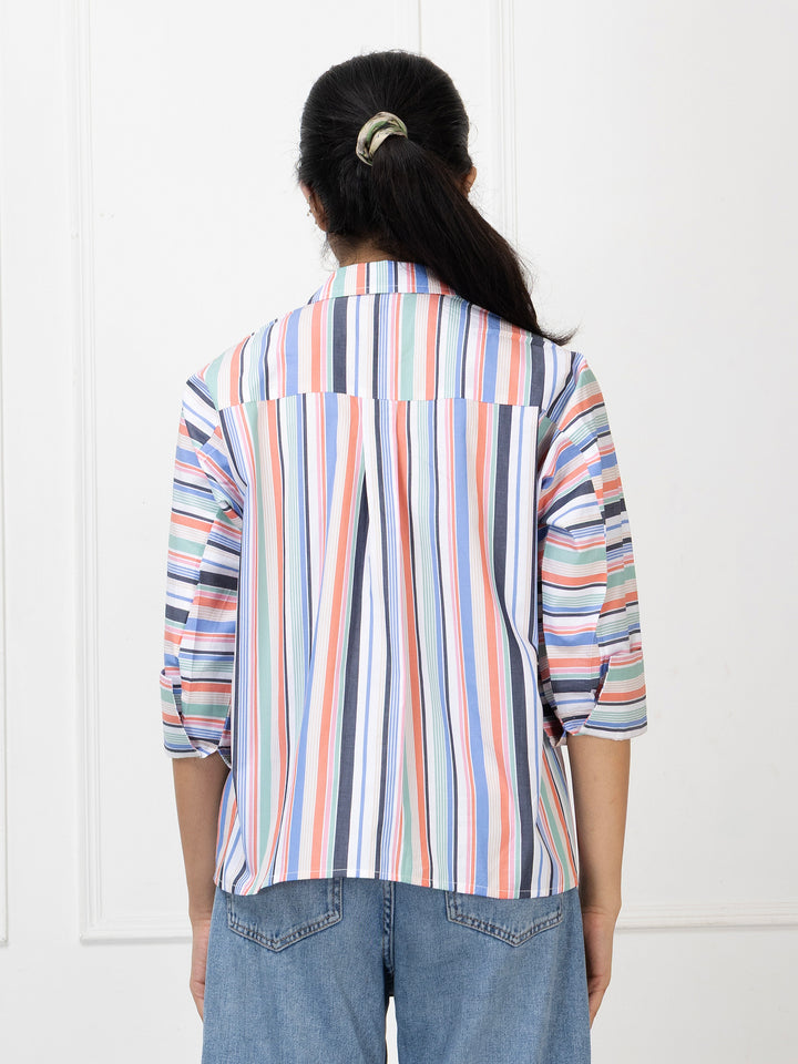 Person wearing a multicolored striped shirt and blue jeans against a white background