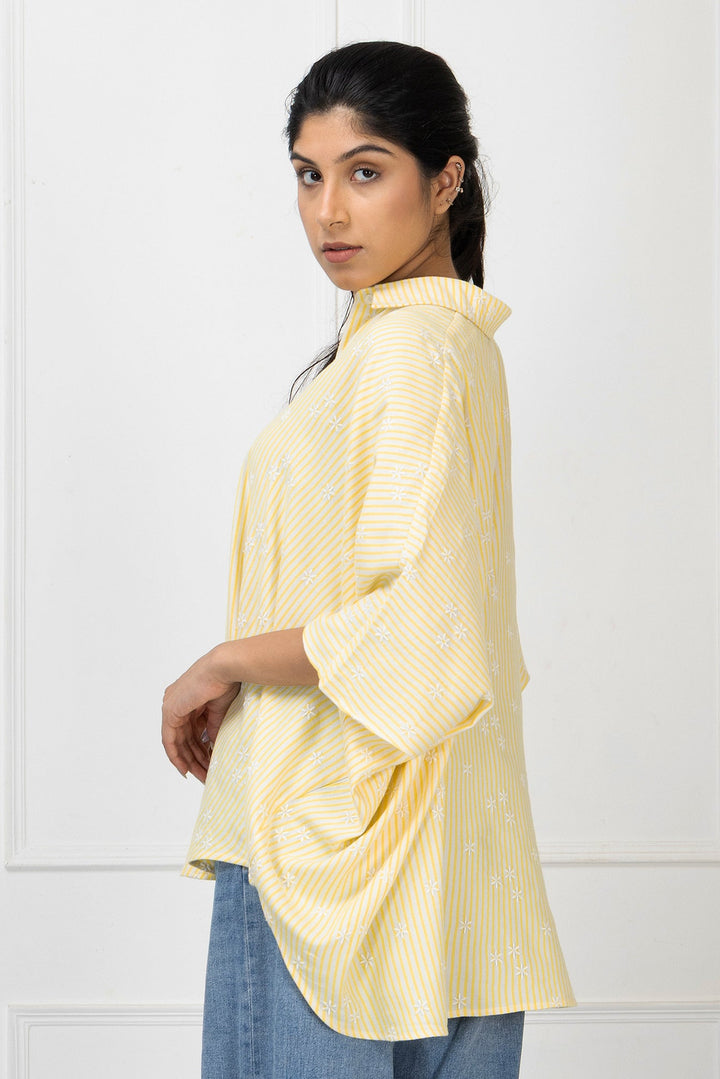 Woman wearing a light yellow striped shirt against a white background