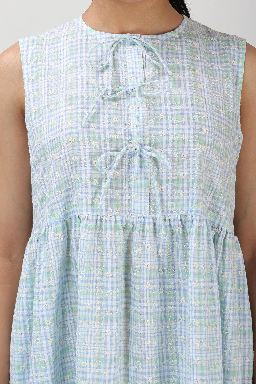 Light blue checkered dress with a tie detail on a plain background
