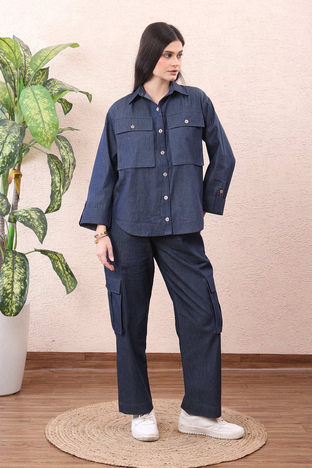 Person wearing a navy blue outfit with a plant and wooden floor in the background