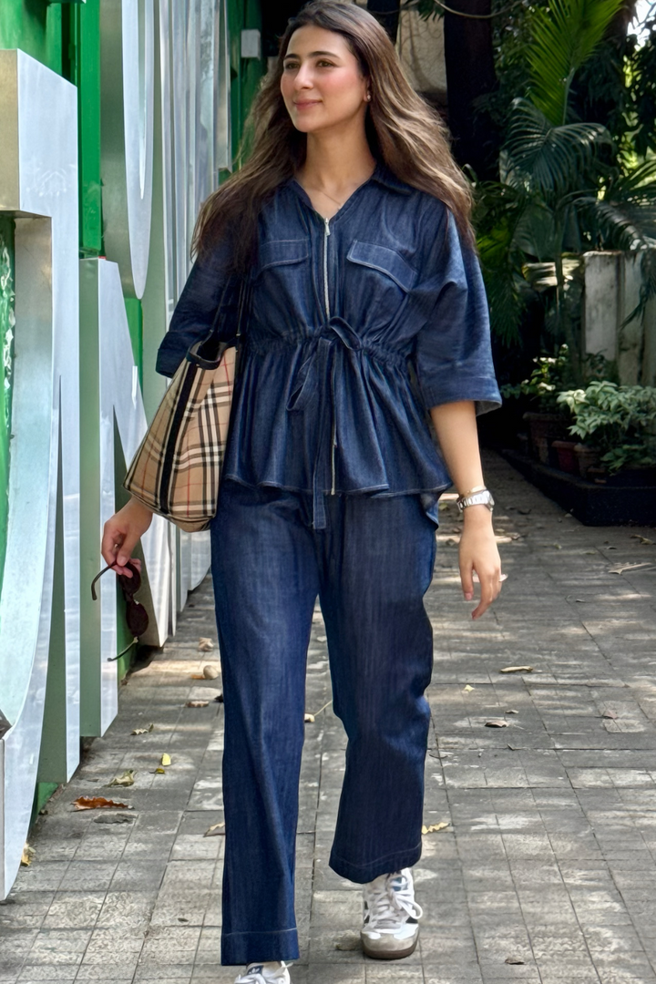 Woman in a blue outfit walking outdoors with greenery in the background