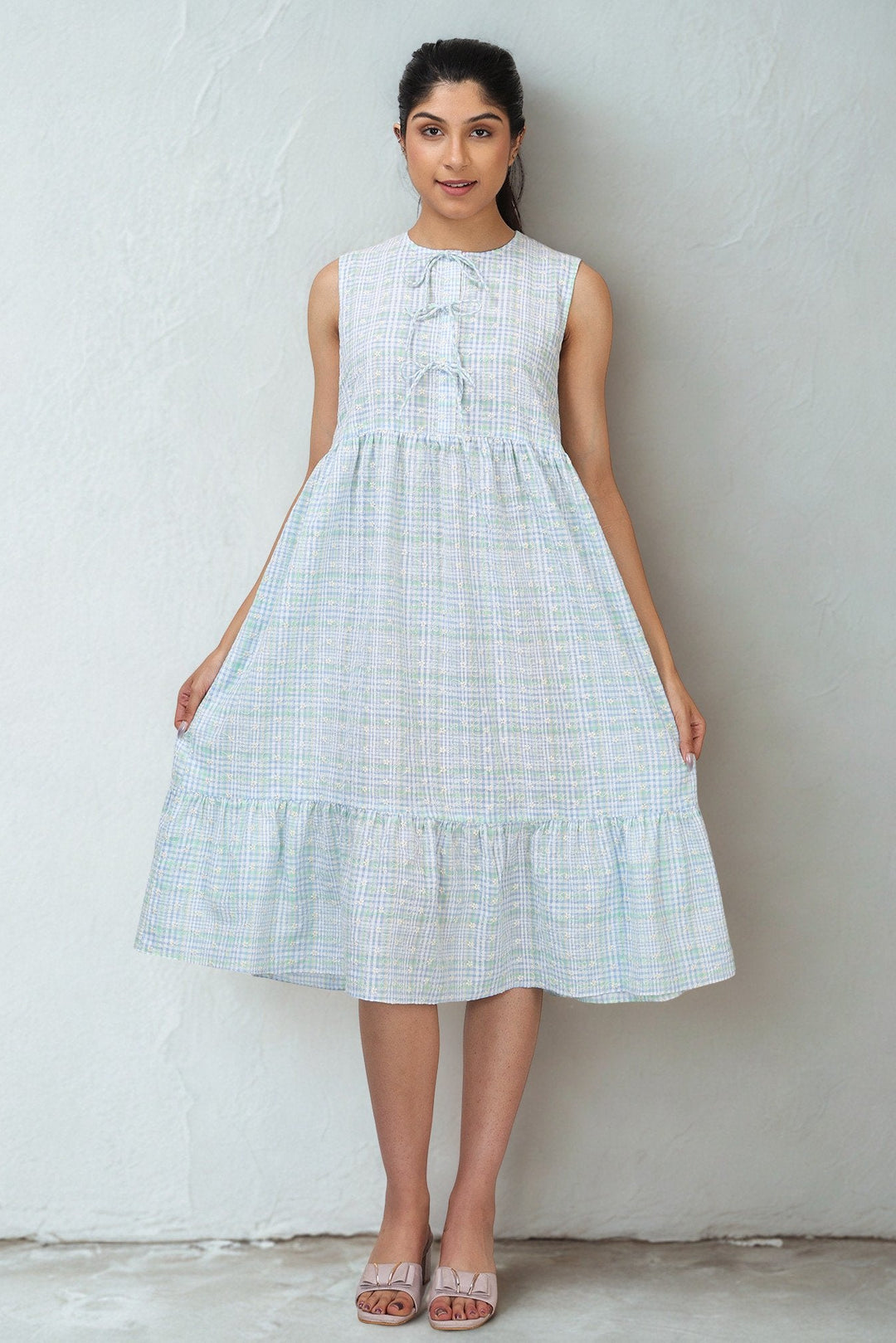 Woman wearing a light blue checkered dress against a plain background