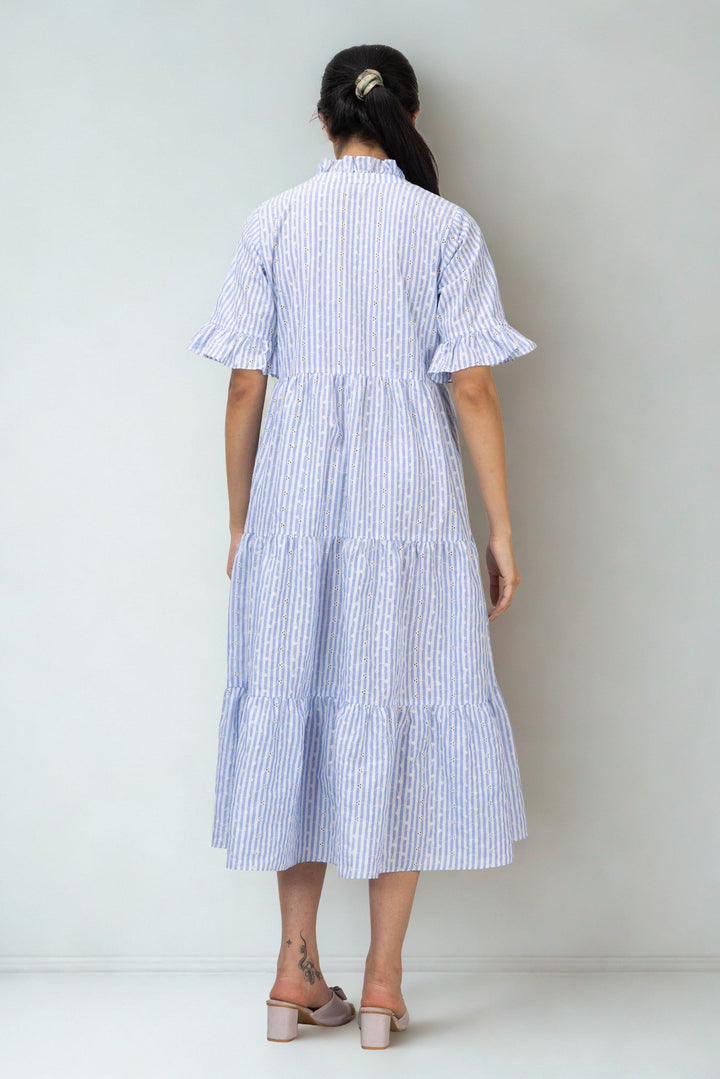 Woman wearing a blue and white striped dress against a plain background
