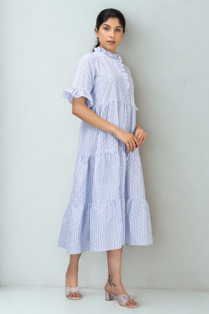 Woman wearing a blue and white striped dress against a plain background