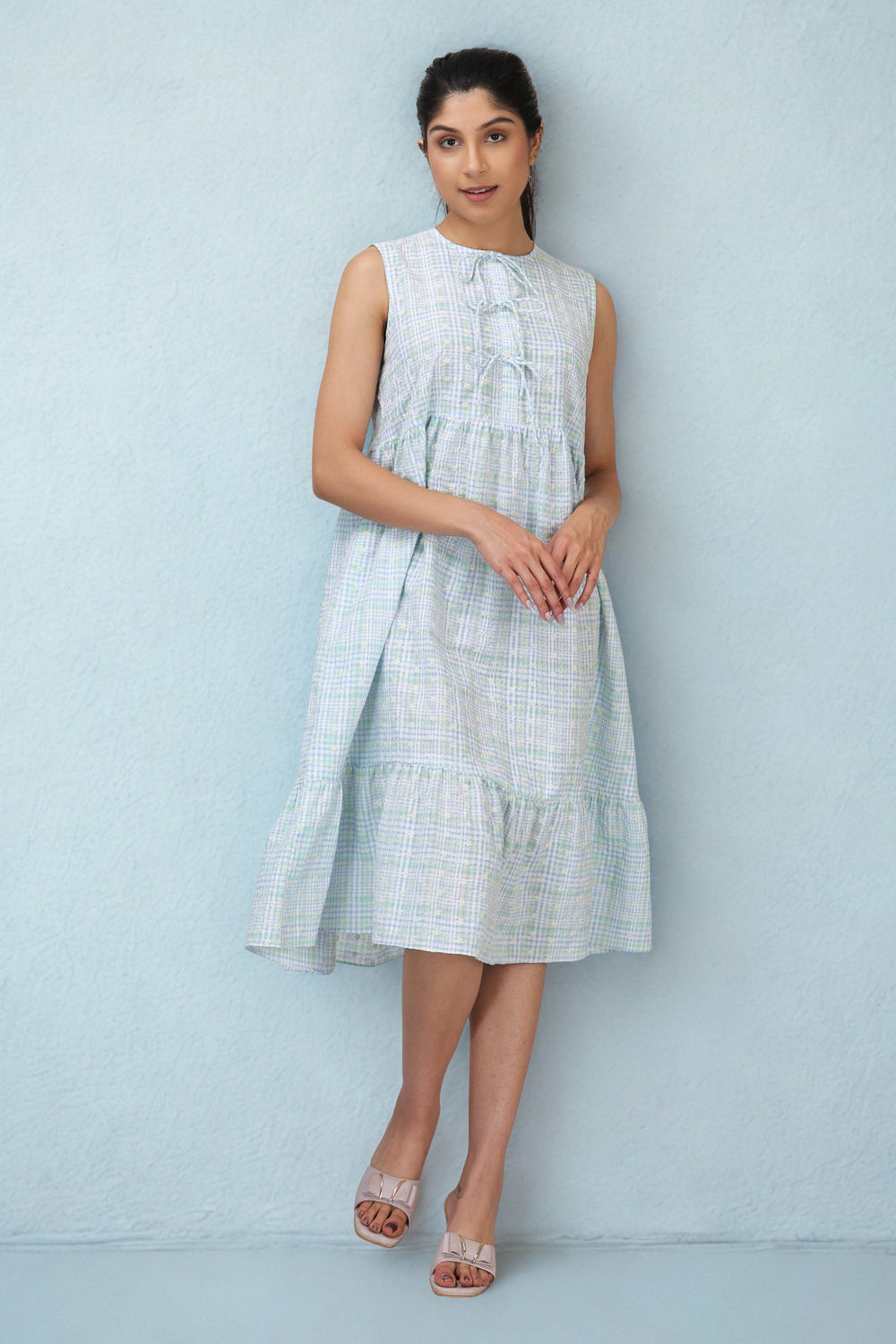Woman wearing a light blue checkered dress against a light blue background