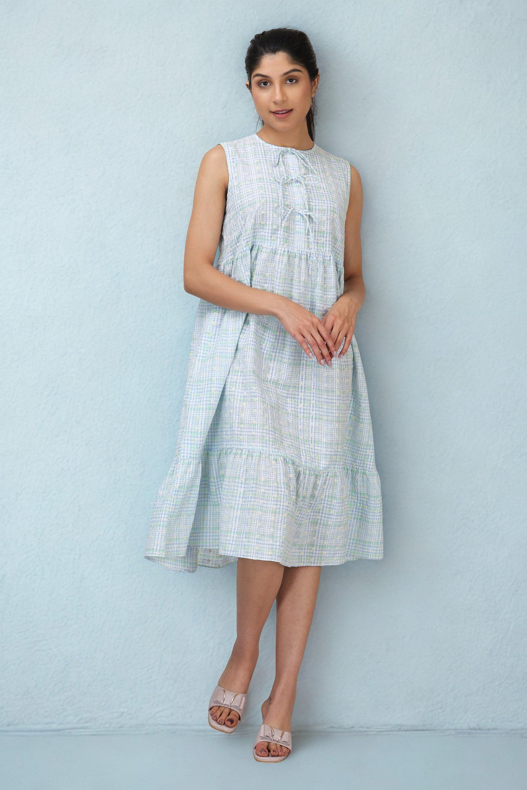 Woman wearing a light blue checkered dress against a light blue background