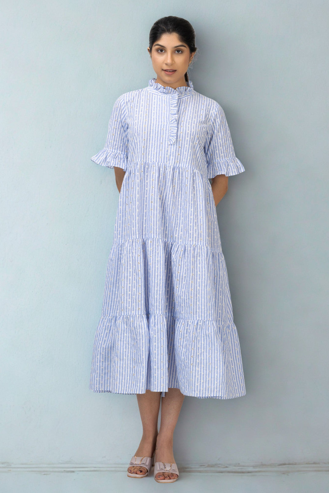 Woman wearing a blue and white striped dress against a gray background