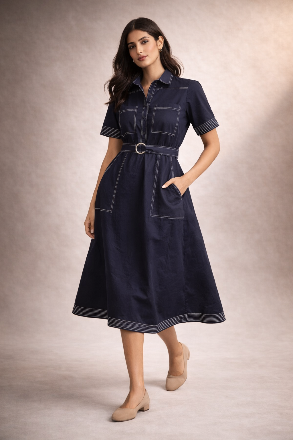 Woman wearing a navy dress with a belt against a neutral background