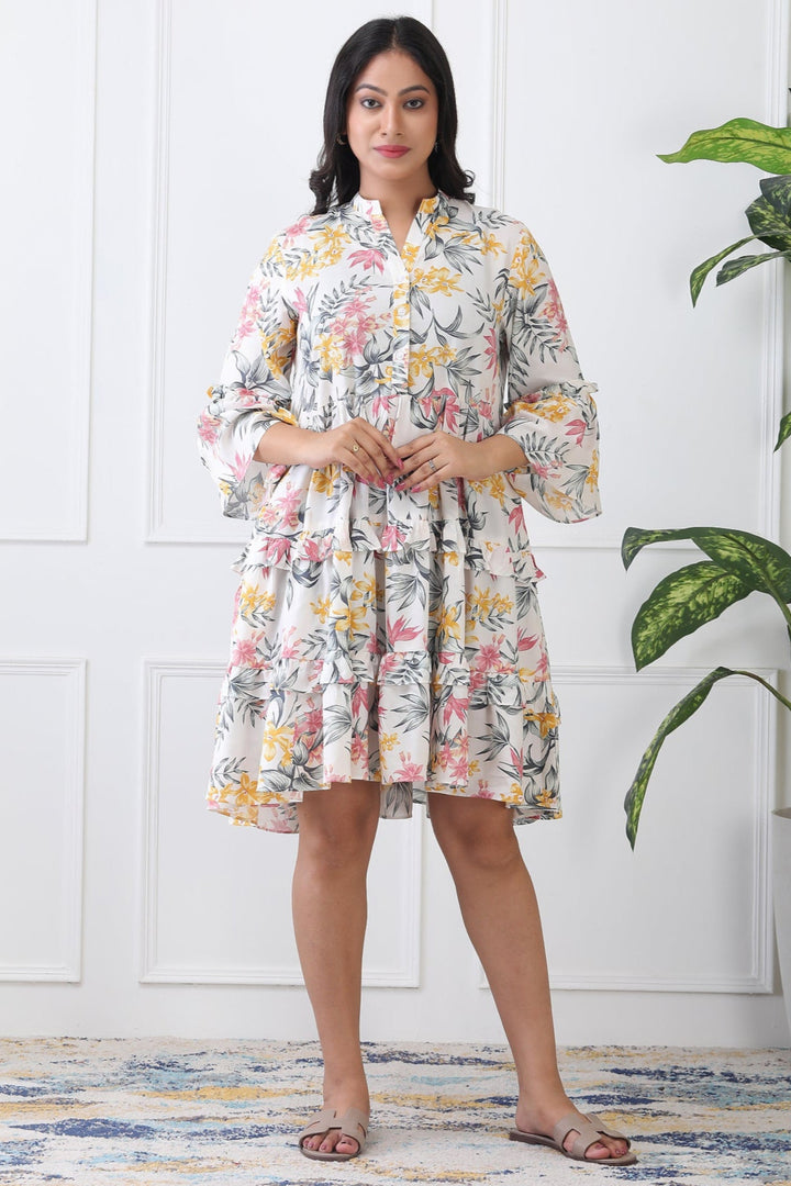 Woman wearing a floral dress standing in a room with a plant.
