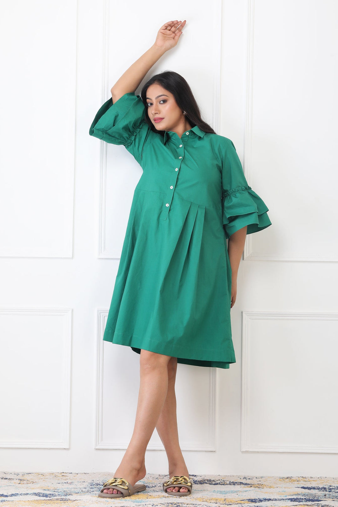 Woman wearing a green dress against a white wall
