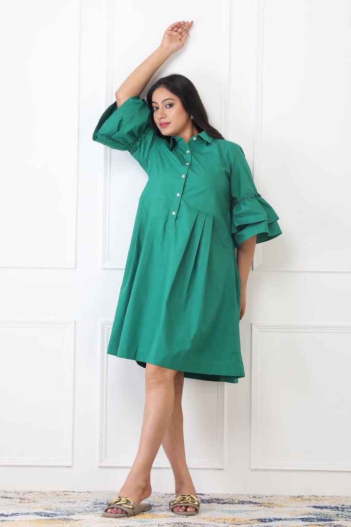 Woman wearing a green dress against a white wall