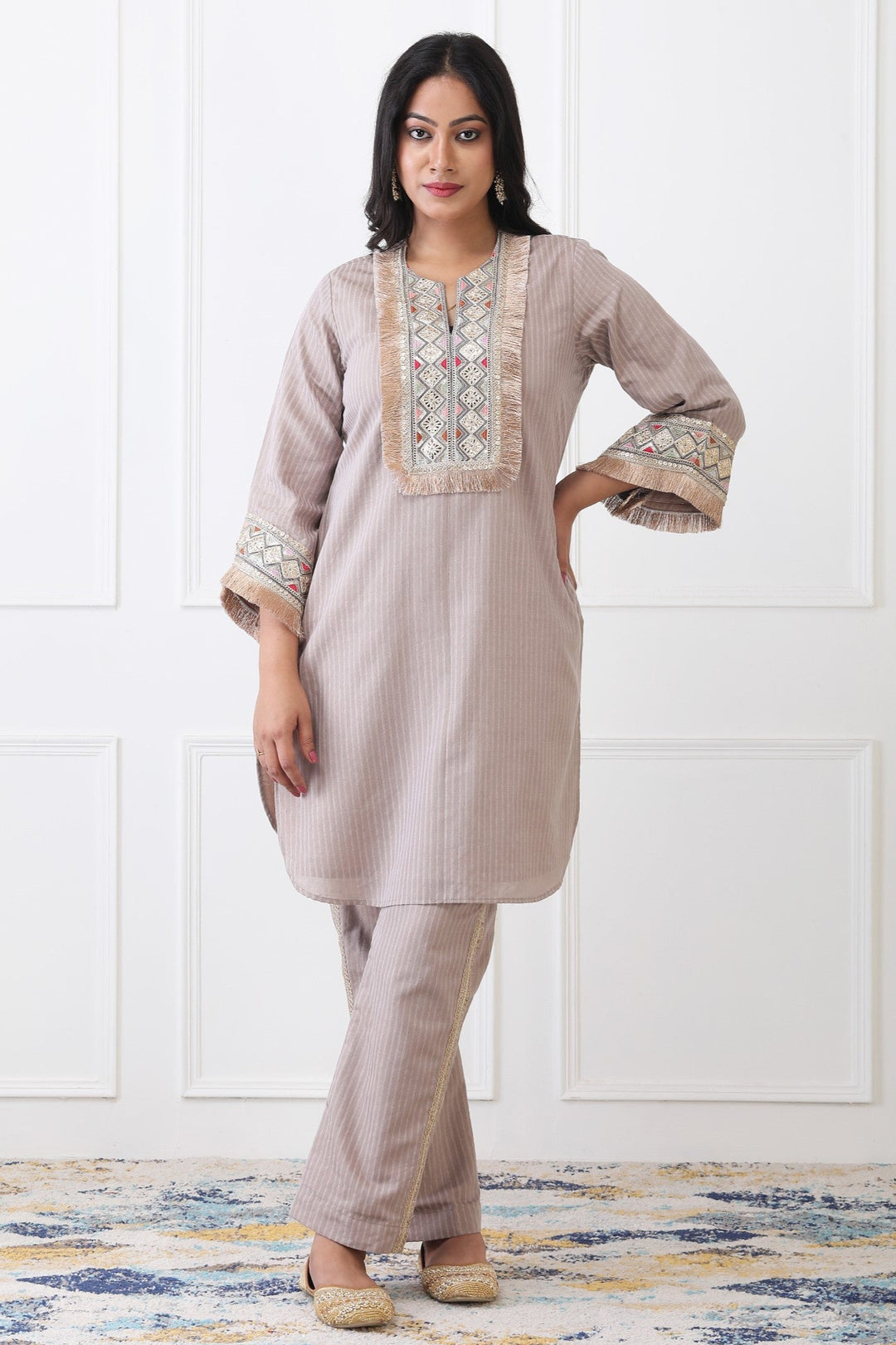 Woman wearing a beige embroidered outfit with a white background