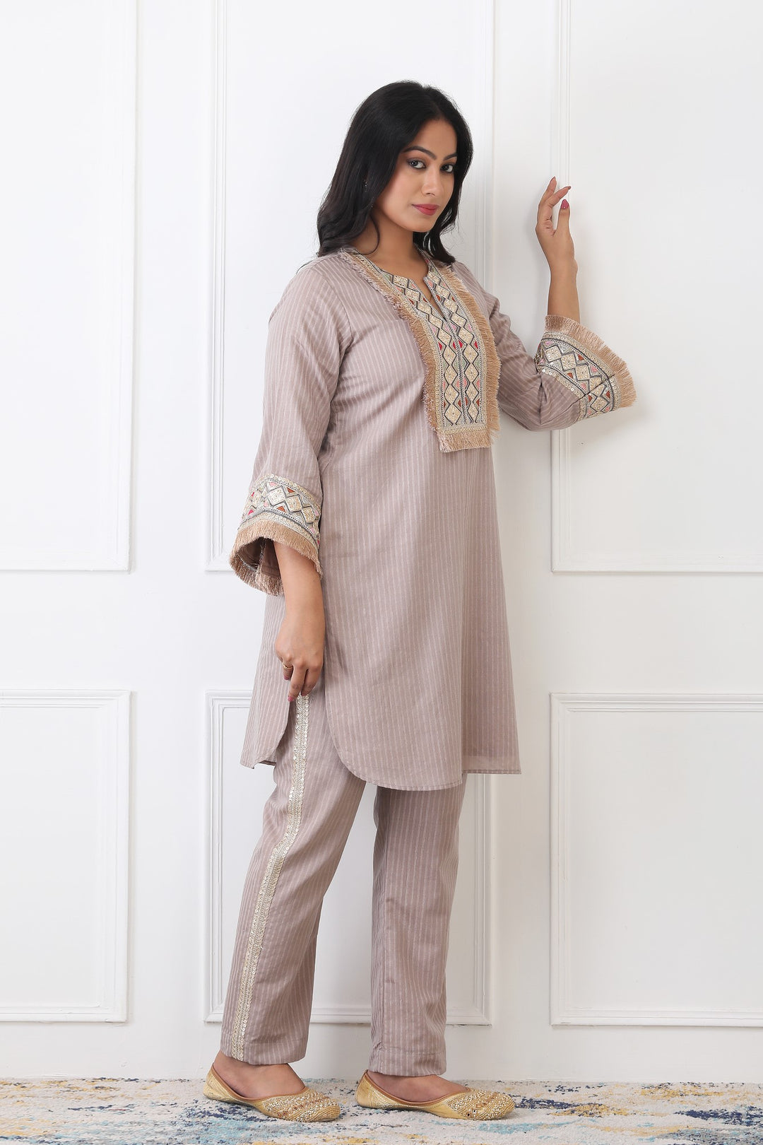 Woman wearing a traditional outfit with embroidered details against a white wall.