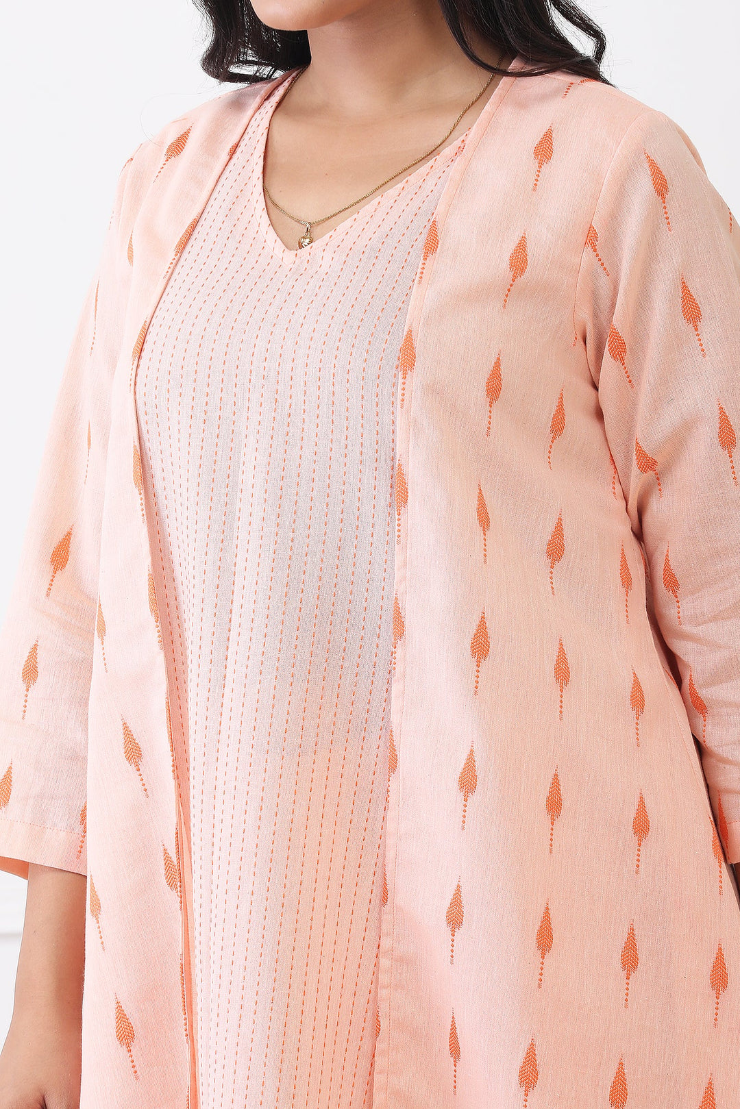 Woman wearing a peach-colored cardigan with a subtle pattern on a white background