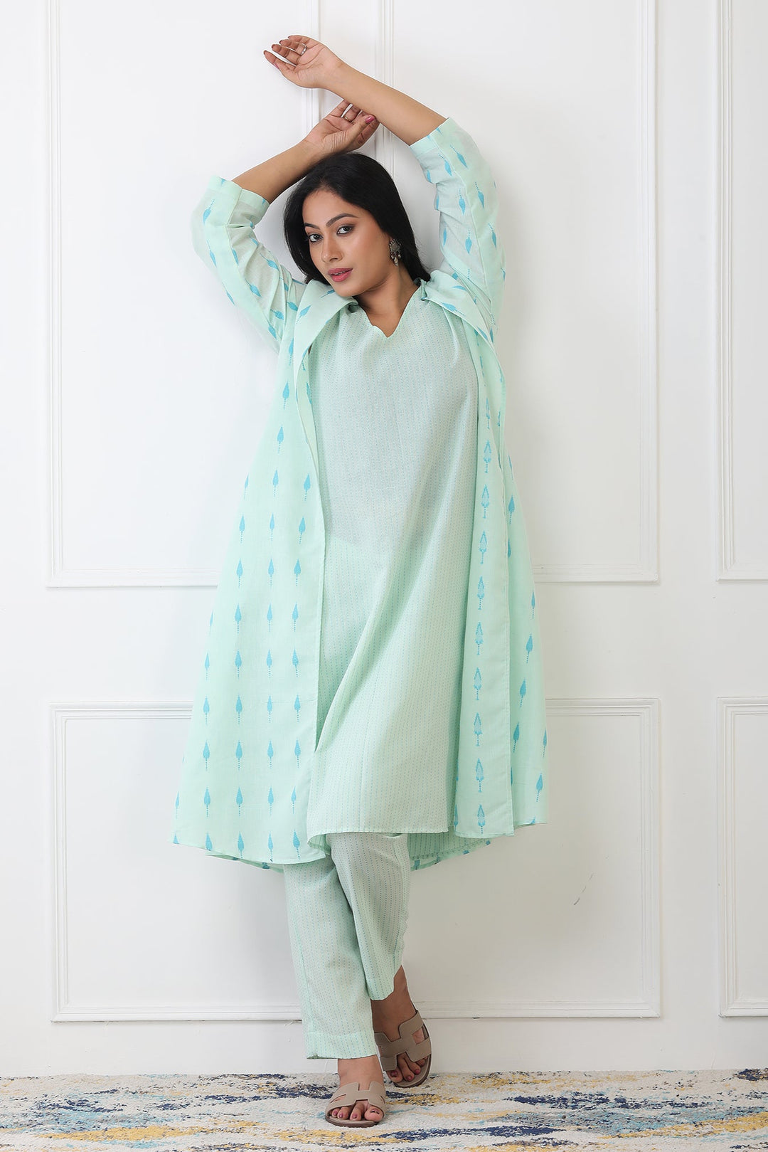 Woman wearing a light green traditional outfit with a white background