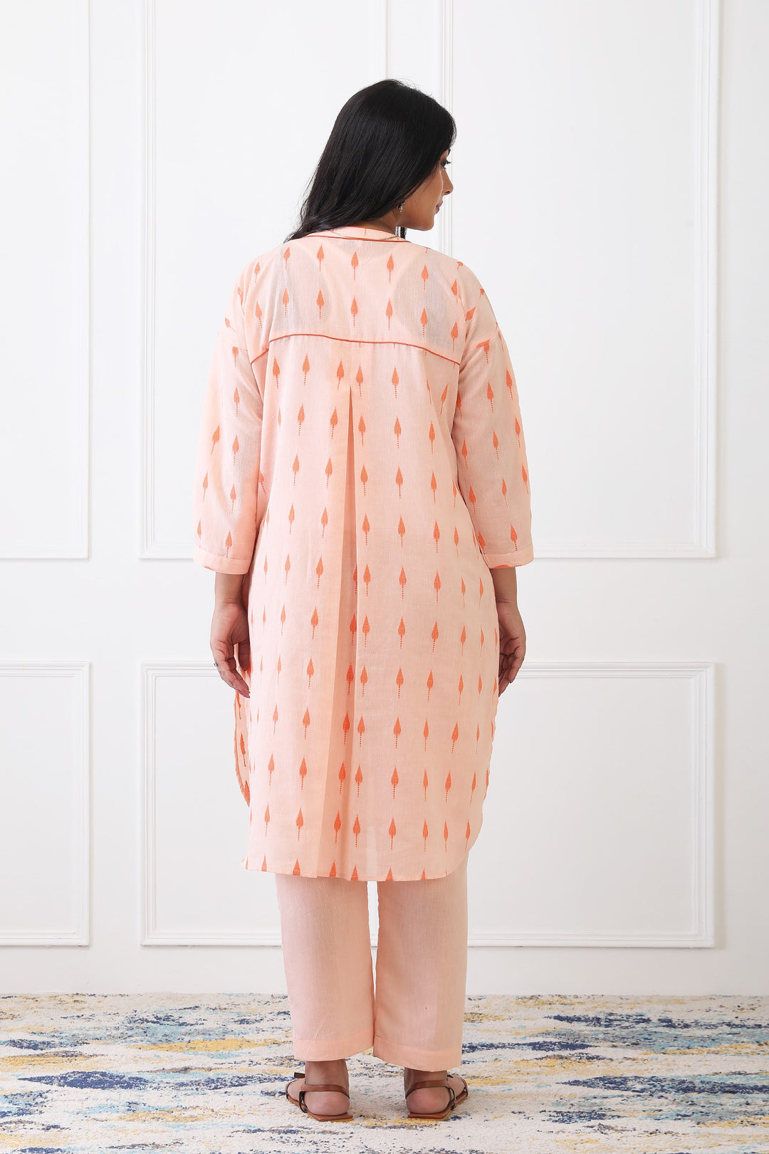 Woman wearing a peach-colored kurta with a white background
