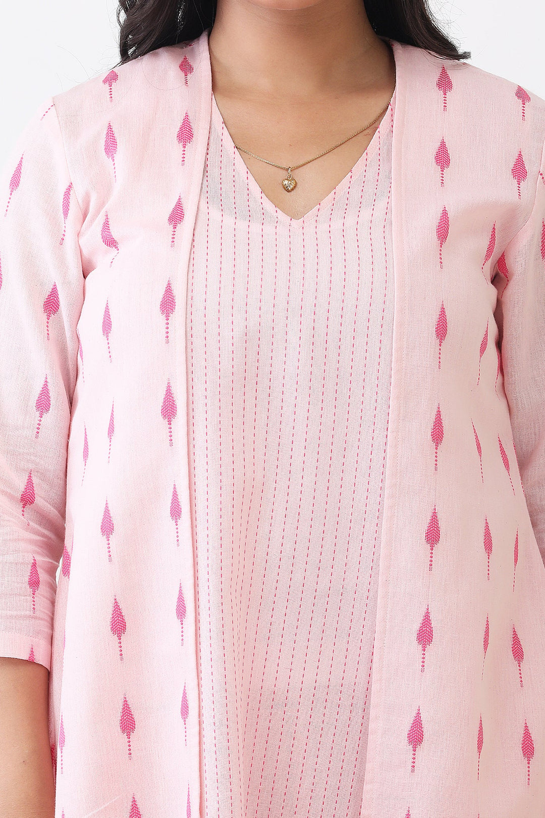 Woman wearing a pink patterned cardigan over a white top with a plain background