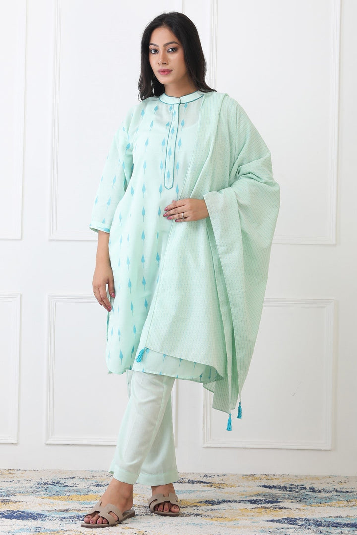 Woman wearing a light green traditional outfit with a white background