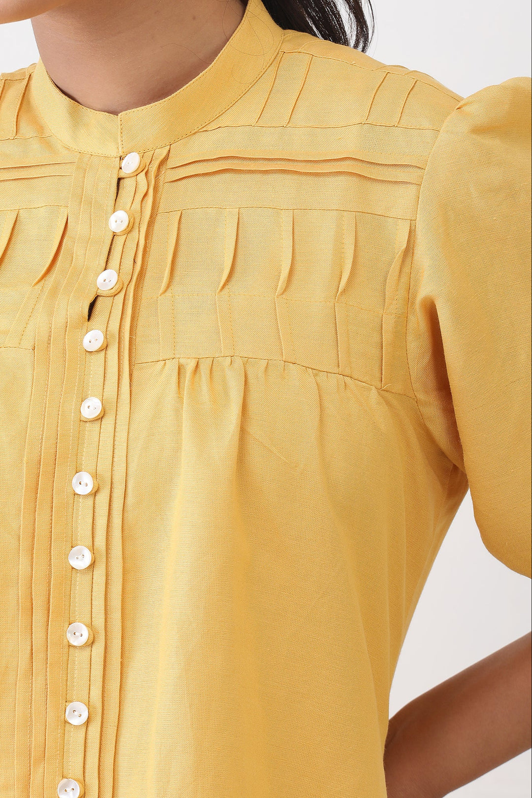 close up of yellow dress with buttons on a white background
