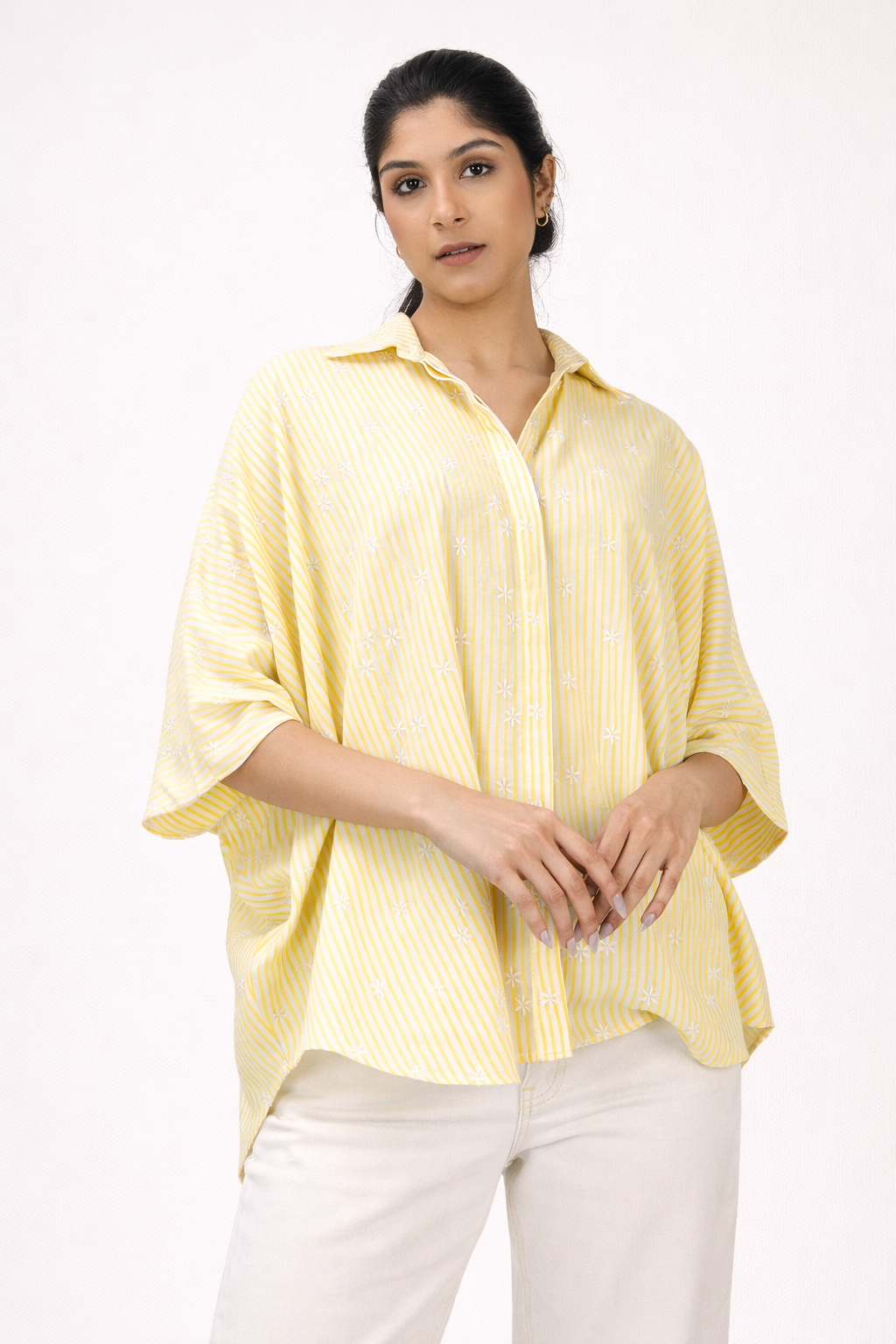 Woman wearing a yellow striped shirt and white pants on a white background