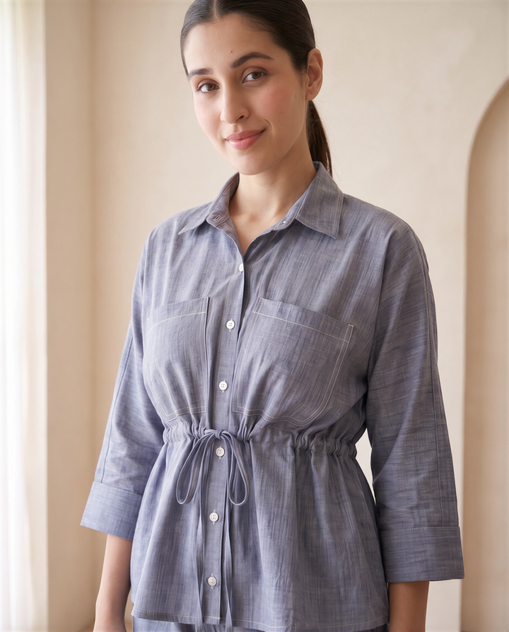 Close-up of the Alexis chambray shirt: oversized chest pockets, contrast topstitching, white buttons and drawstring waist